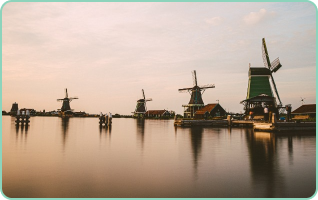 Imagem de moinhos de vento próximo a um lago em Amsterdam.